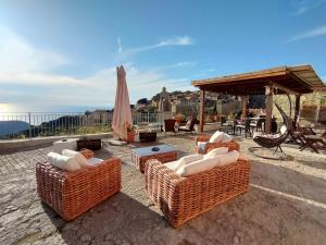 een groep rieten stoelen en een parasol op een patio bij B&B Airone in Isola del Giglio