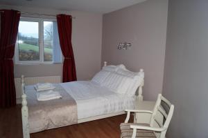 ein Schlafzimmer mit einem Bett, einem Stuhl und einem Fenster in der Unterkunft Clonmurr B&B in Ballyroney