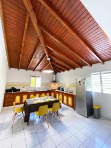a kitchen with a black table and yellow chairs at La Villa Ixora, magnifique Villa avec Piscine in Les Abymes