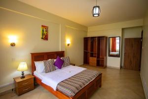 - une chambre avec un grand lit et une table de nuit dans l'établissement ST STEVENS SUITES, ENTEBBE, à Entebbe