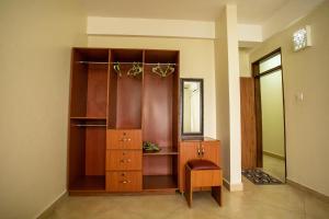 Habitación con armario, vestidor y silla. en ST STEVENS SUITES, ENTEBBE en Entebbe