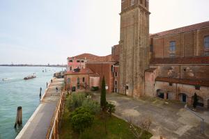 un edificio con una torre dell'orologio accanto all'acqua di Ostello AMDG a Venezia