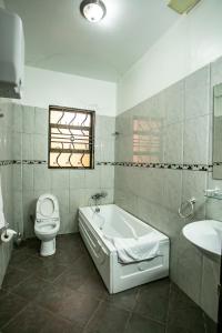 La salle de bains est pourvue d'une baignoire, de toilettes et d'un lavabo. dans l'établissement ST STEVENS SUITES, ENTEBBE, à Entebbe