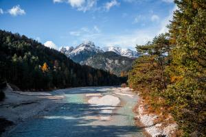 un río con montañas cubiertas de nieve en el fondo en Alpe Chalets Goldener Hirsch en Scharnitz