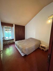 a bedroom with a bed and a chair in it at Casa en Villa el Chocón, Neuquén in Villa El Chocón