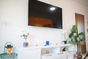 a white shelf with a flat screen tv on a wall at Happy to welcome you too modern in Santiago de los Caballeros