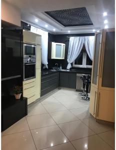 uma cozinha com armários pretos e piso em azulejo branco em Apartament em Puck