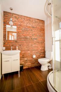 a bathroom with a brick wall and a sink and a toilet at Apartament 33 Poronin in Poronin