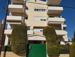 een gebouw met struiken ervoor met een groene deur bij Marilena's Apartment in Rafina