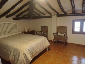 a bedroom with a bed and two chairs at Casa Rural 643km in Villatuerta