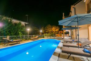 a swimming pool at night with chairs and an umbrella at Villa Ljubica 2 in Vodice +79 photos