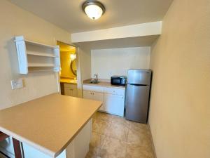 eine Küche mit einem Kühlschrank aus Edelstahl und weißen Schränken in der Unterkunft Big Chile Inn & Suites in Las Cruces