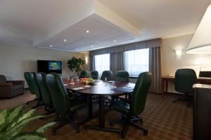 Holiday Inn Laval Montreal, an IHG Hotel في لافال: قاعة اجتماعات مع طاولة وكراسي خضراء