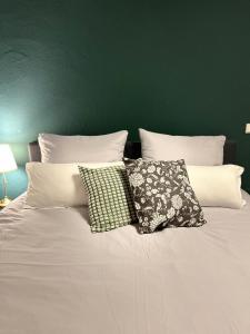 a white bed with two pillows and a green wall at Ferienwohnung Saargauliebe in Saarburg