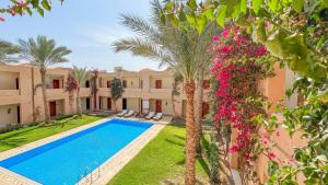 an exterior view of a villa with a swimming pool and palm trees at Gemma Resort in Marsa Alam City