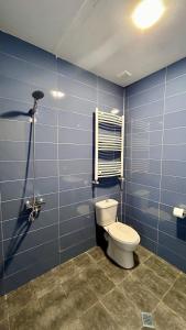 uma casa de banho azul com um WC e uma janela em Persati View em Kutaisi