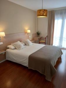 um quarto com uma grande cama branca e uma cadeira em Littore Tormes Alojamiento, Parking gratis y Piscina em Salamanca