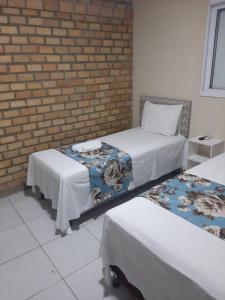 a room with two beds and a brick wall at Riacho do Recanto Pousada in Barreirinhas