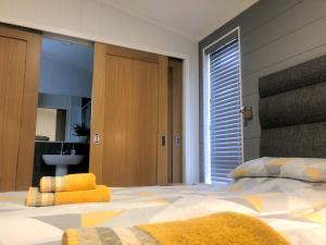 Un dormitorio con una cama grande con almohadas amarillas. en Shropshire Lodges - Romantic Luxury Hot Tub Breaks, en Bridgnorth