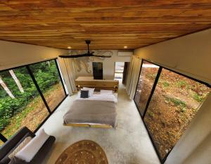 にあるPandanus Lodge & Retreatsの大きな窓が備わる小さな家の中のベッドルーム1室です。