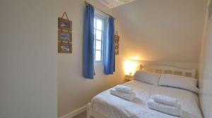 a bedroom with a bed with blue curtains and a window at 36 Tudor Court, Tolroy Manor in Saint Erth +13 photos