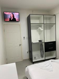 um quarto com uma televisão na parede e um armário em HHC Apartments Kronos em Paramaribo
