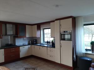 una cocina con armarios blancos y una ventana en Vakantiehuis Stobben, en Bourtange