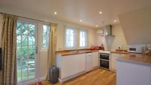 a kitchen with white cabinets and a large window at 36 Tudor Court, Tolroy Manor in Saint Erth
