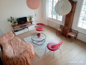 een woonkamer met rode stoelen en een tv bij Auprès de mon arbre in Thuir