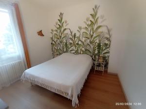 een wit bed in een kamer met een plant bij Auprès de mon arbre in Thuir