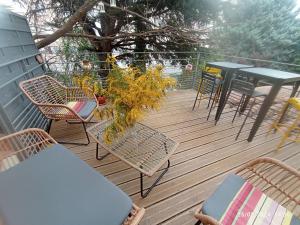 een houten terras met stoelen en tafels en een tafel bij Auprès de mon arbre in Thuir
