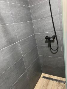 una doccia con parete piastrellata grigia e soffione di Residence Hill A83 a Kopaonik