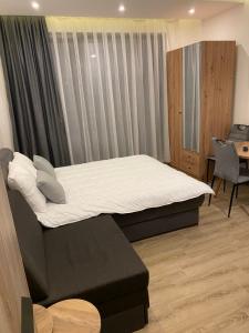 una camera da letto con letto con lenzuola bianche e scrivania di Residence Hill A83 a Kopaonik