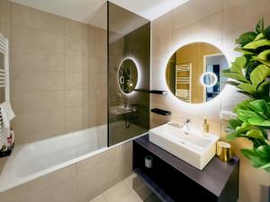 a bathroom with a sink and a tub and a mirror at AlpenLuxus' KAISER LODGE with rooftop pool & underground car park in Vienna