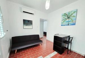 a living room with a black couch and a table at Sweet Sunset II- Rompeolas Beach in Aguadilla