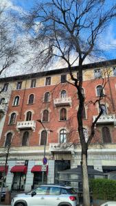 um carro branco estacionado em frente a um grande edifício de tijolos em Duran Apartment: Cozy two-room apartment em Milão