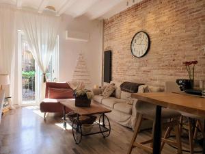a living room with a couch and a clock on a brick wall at EF7 Beds & Family in Tarragona