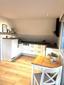 a kitchen with white cabinets and a wooden table at Auszeit Norddeich mit Seeblick in Norddeich