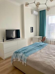 a bedroom with a bed and a flat screen tv at ЖК бизнес класса Atameken, рядом ТРЦ Мega по Розыбакиева in Almaty
