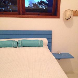 ein Schlafzimmer mit einem Bett mit einem Hut am Fenster in der Unterkunft Casa charmosa na Praia de Santo Andre/ Bahia in Santa Cruz Cabrália