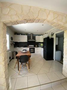 uma cozinha com uma mesa e um frigorífico preto em Maison chaleureuse aux portes de Tours. em Saint-Branchs