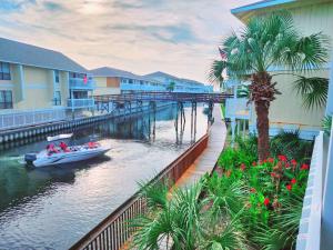 a boat on a river with buildings and palm trees at Boathouse Condo, Downtown Destin Harbor, Private Beach Access, Waterfront, on Golf course, Water Taxi pickup in Destin +20 photos