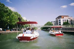 two boats in a river with people on it at Paris Central Design Jardin & Terrasse privé in Paris