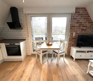 a kitchen with a table and chairs in a room at Ferienwohnung Auszeit Norddeich mit Seeblick I 5 Minuten zu Fuß zum Meer in Norddeich