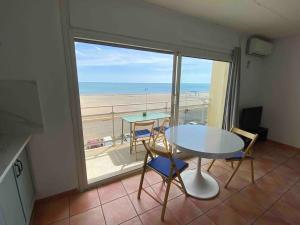 a table and chairs in a room with a view of the beach at Appt T3 front de mer belle vue in Narbonne
