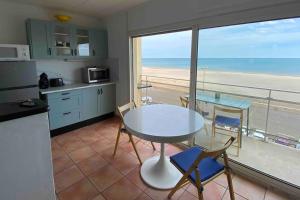 a kitchen with a table and chairs and a view of the beach at Appt T3 front de mer belle vue in Narbonne