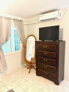 a room with a dresser with a television and a mirror at Andeve's tranquil beautiful home in Montego Bay +33 photos