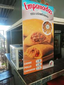 un panneau pour un distributeur empanadas sur un comptoir dans l'établissement Waterfall Hostel, à Los Anastacios