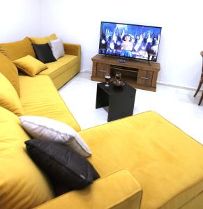a living room with two yellow couches and a tv at Villa Musica in Balchik