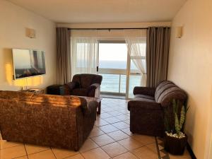 a living room with a couch and two chairs and a window at Stella Maris Flat 93 Amanzimtoti in Amanzimtoti
